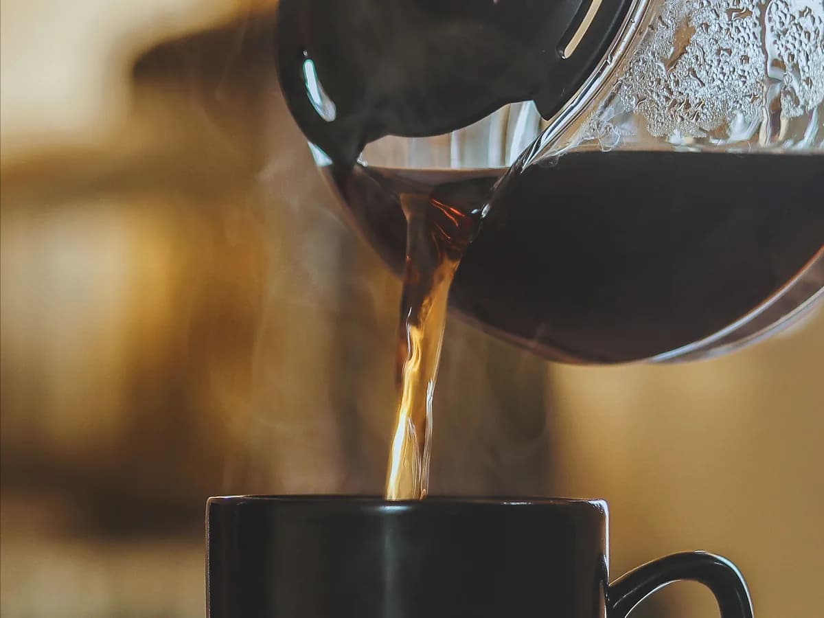 Filter kafa se sipa iz staklenog bokala u crnu šolju
