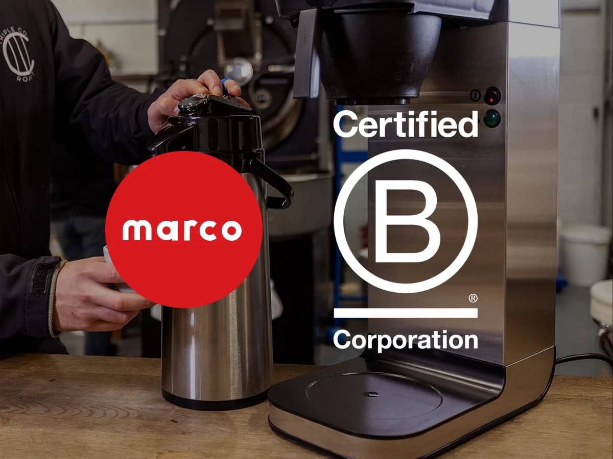 Barista toči kafu iz termosa pored Marco BRU aparata, preko slike logotipi Marco i B Corp