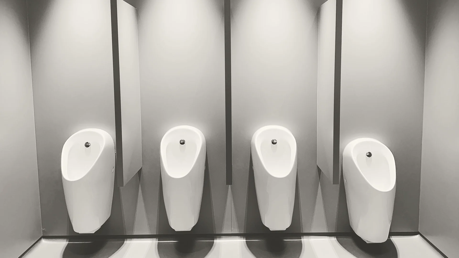 Clean modern café restroom stalls with a spotless toilet, tiled walls, and dark partition doors, showing a tidy restroom area ready for customer use