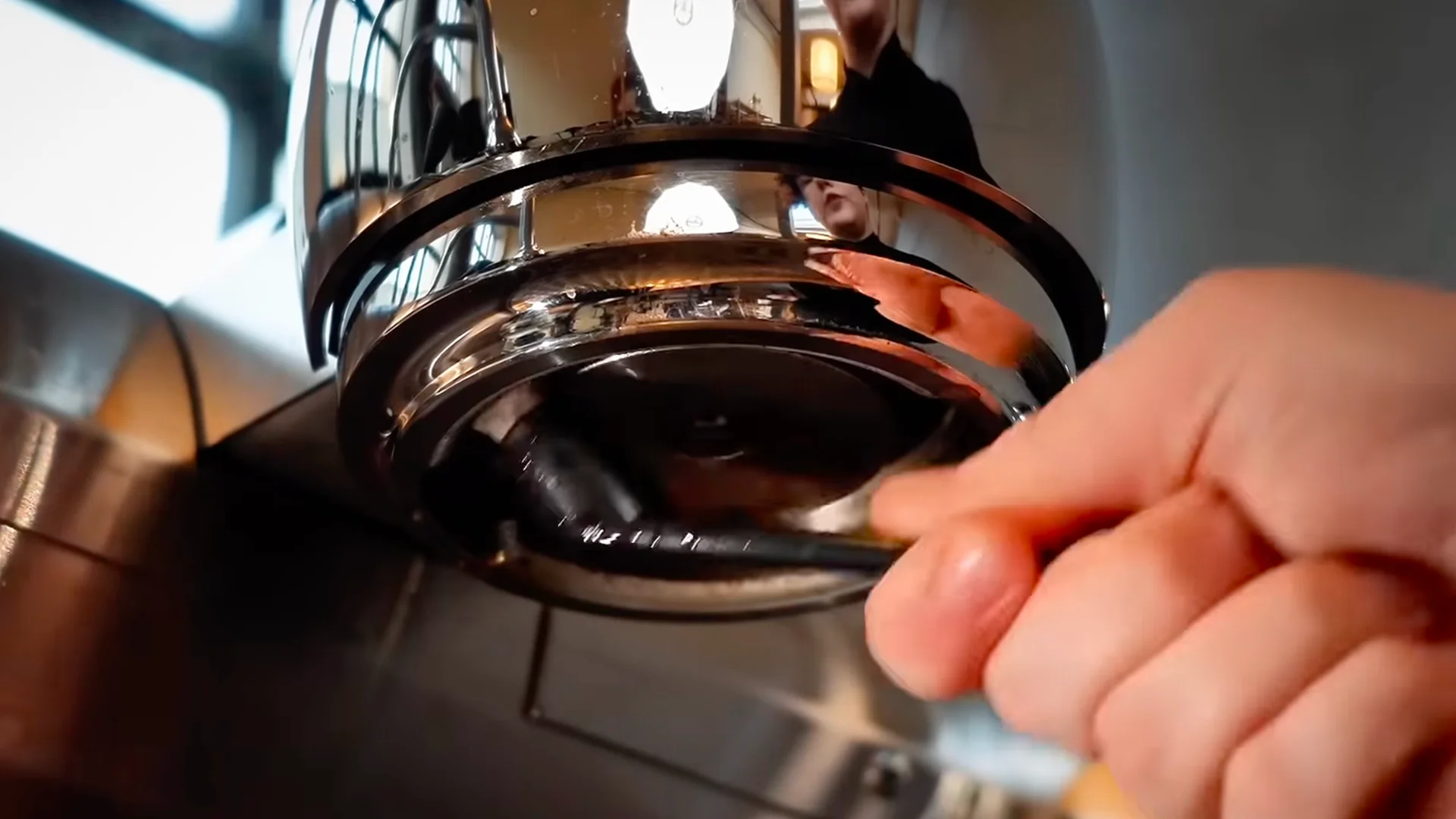 Café staff member locking a portafilter into a commercial espresso machine during routine coffee preparation or cleaning