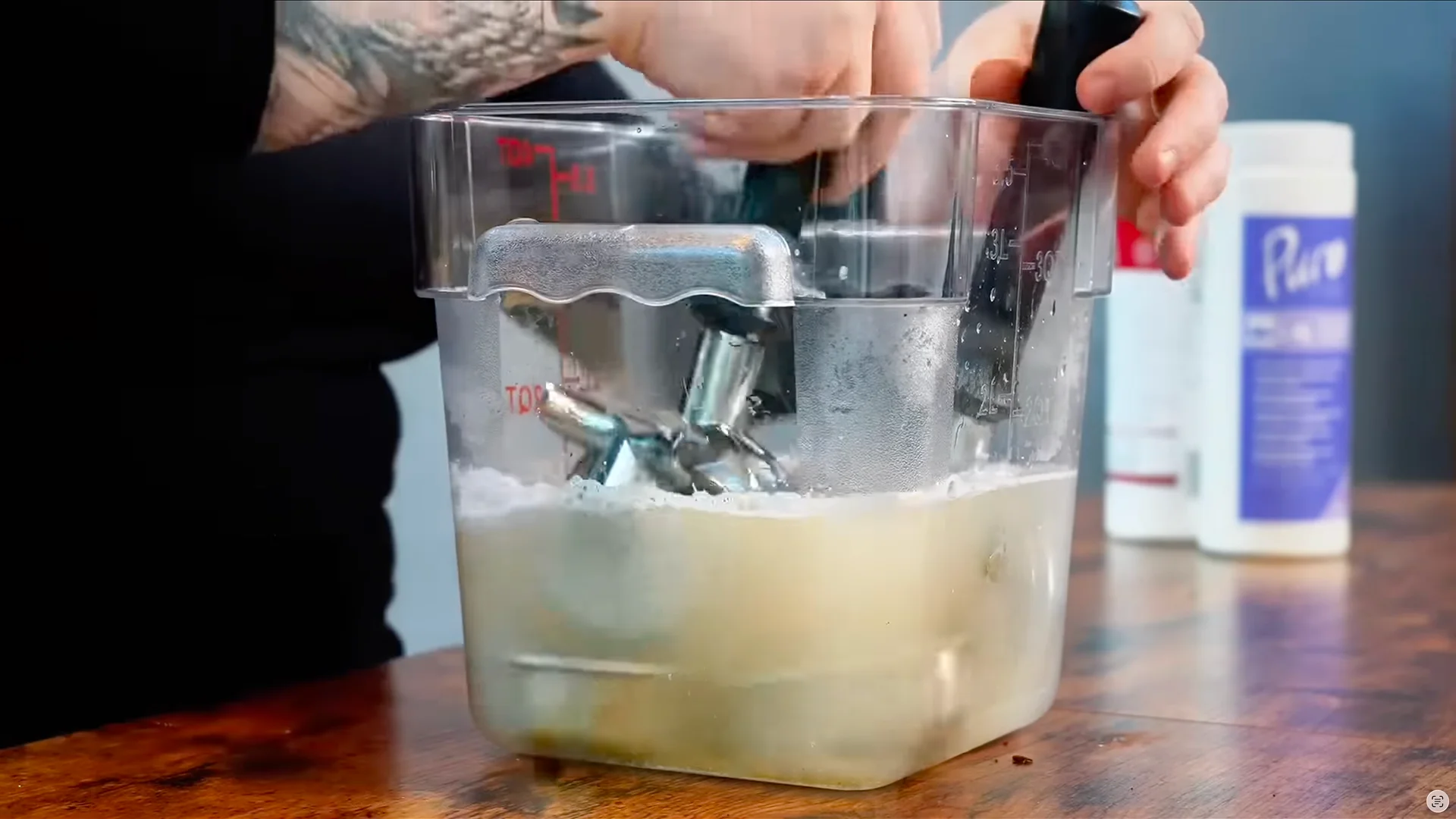 Staff member scrubbing espresso machine portafilter parts with a brush in a soaking container during café equipment cleaning